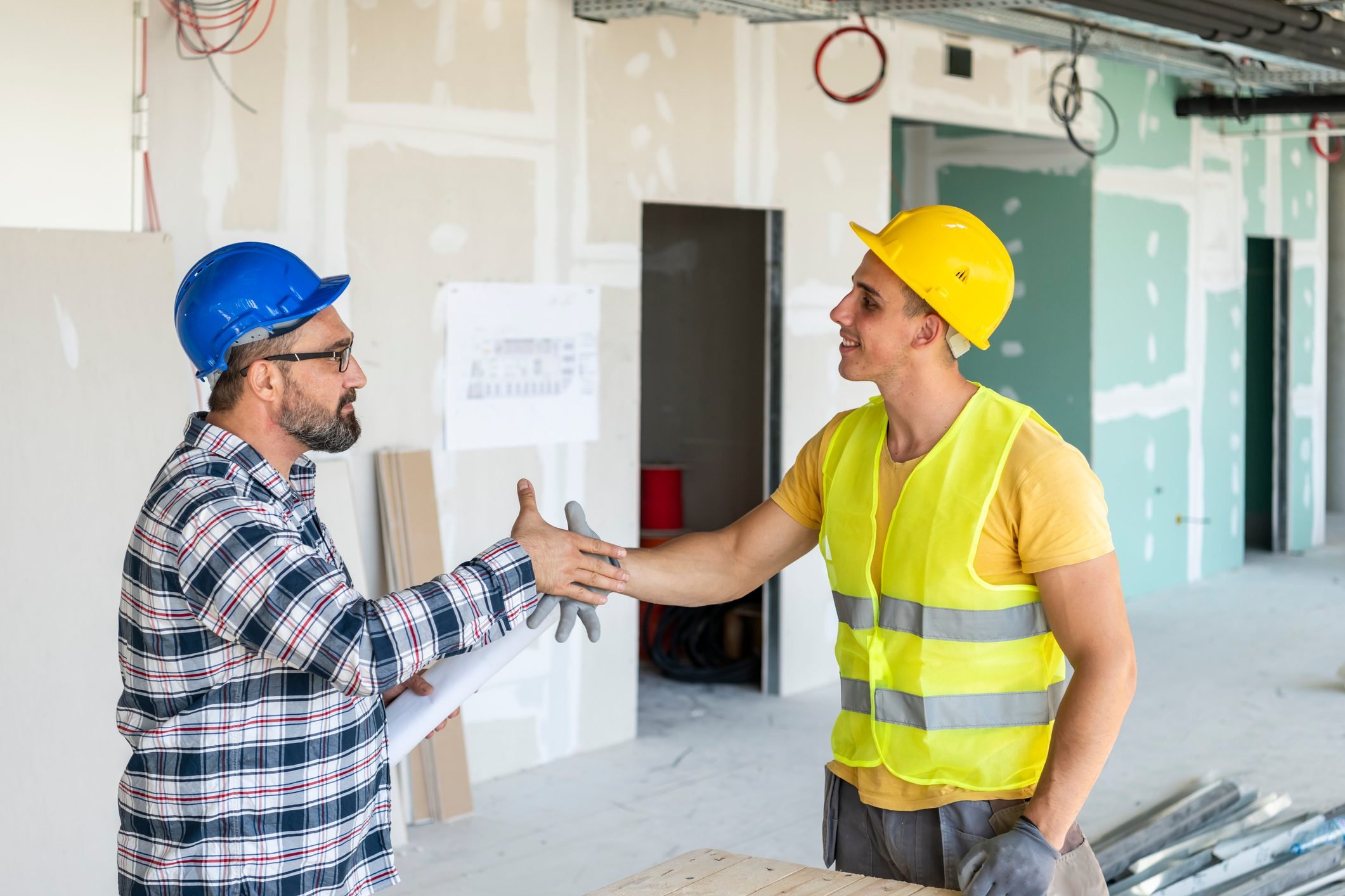 Engineer and architect handshake at meeting with successful construction project.Architect and building engineer have handshake on construction site. Building workers shaking hand inside industrial objec