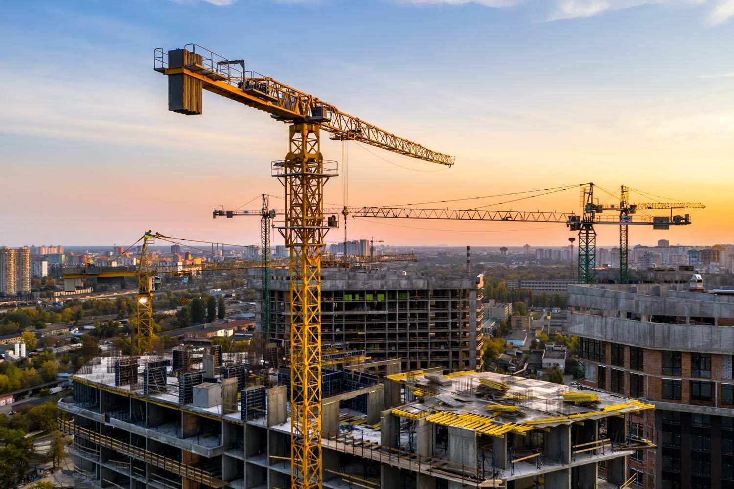 Construction Site of an apartment building seen pictured at sunset with construction cranes erected in the background