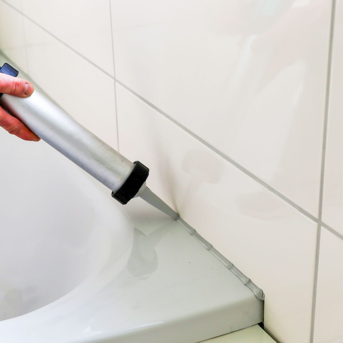 Man Sealing A Bath Or Basin With Silicone