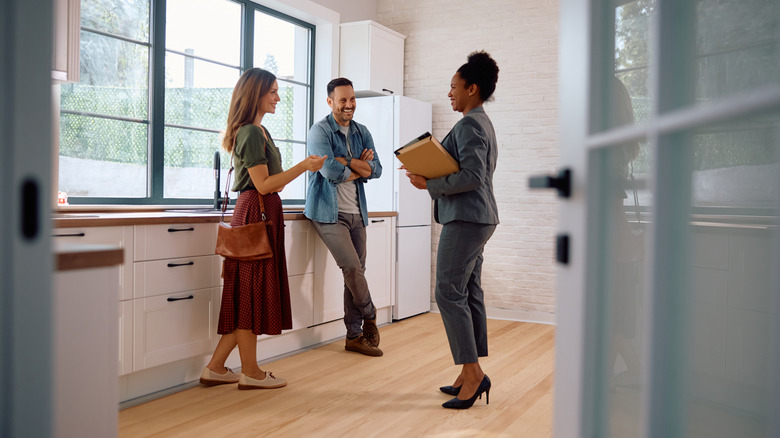 Realtor montrant un couple une cuisine en maison à vendre