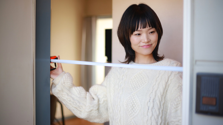 Une femme mesure la largeur d'une porte