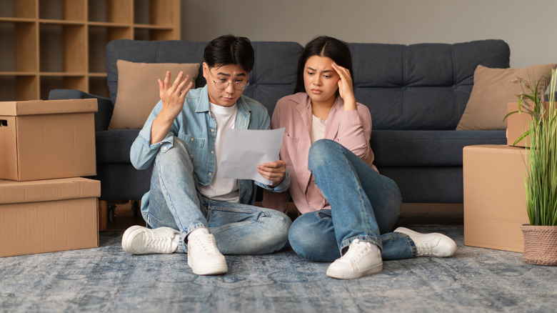 Un couple est assis près d'un canapé tout en regardant leur liste de contrôle en mouvement