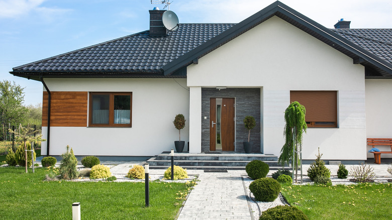 Accueil avec extérieur blanc, toit noir et porte en bois