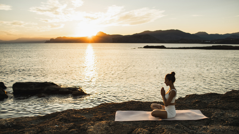 Femme faisant du yoga sur l'île pendant le coucher du soleil