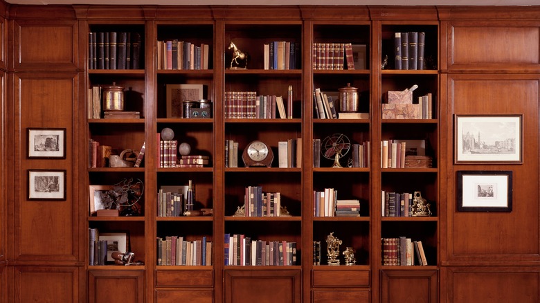 Une bibliothèque brune noyer remplie de livres et d'ornements.