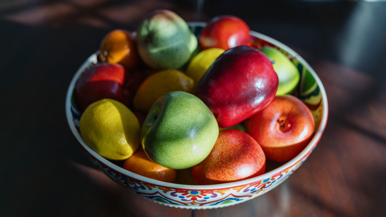 Un bol de fruits pleins de pommes de couleurs et de teintes différentes.