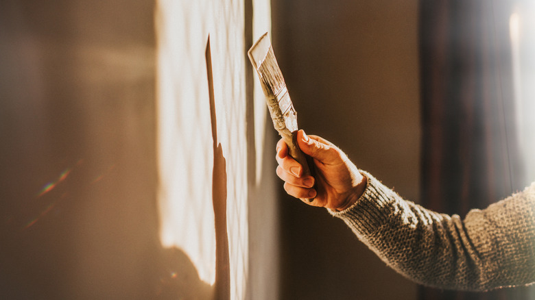 Un homme peignant un mur et tenant un pinceau.