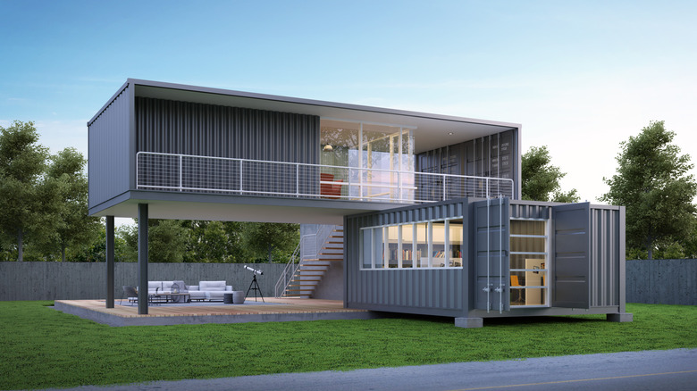 Deux conteneurs d'expédition gris à angle l'une de l'autre avec des fenêtres et des balcons.