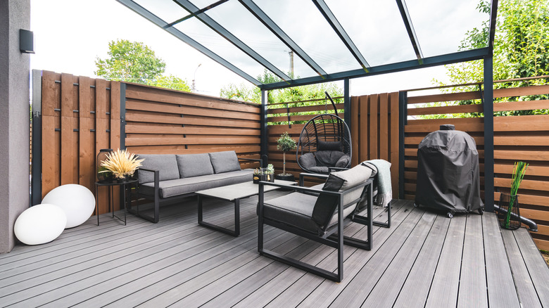Une terrasse moderne avec des meubles gris et des murs en bois.