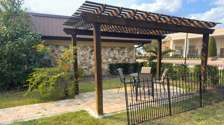 Une pergola avec un sol pavé et des sièges autour d'une petite table.