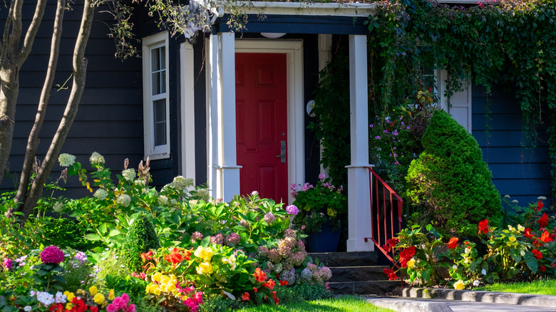L'entrée d'une maison avec une porte rouge et des plantes luxuriantes.