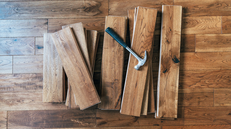 Marteau sur un tas de planches de parquet en chêne massif