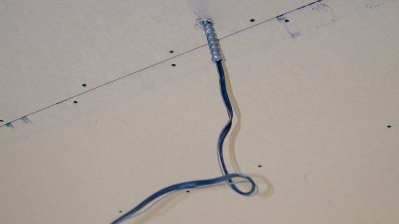 Câblage dépassant d'un plafond à travers un trou