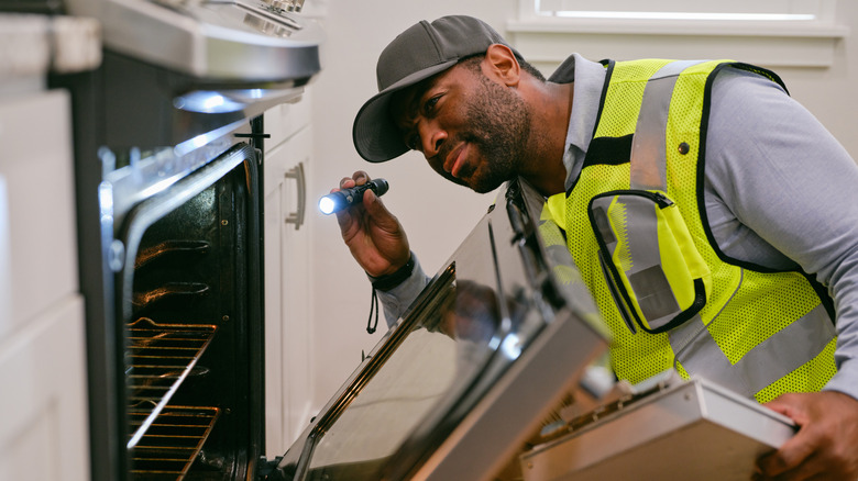 Inspecteur vérifiant les appareils de cuisine, regardant le four