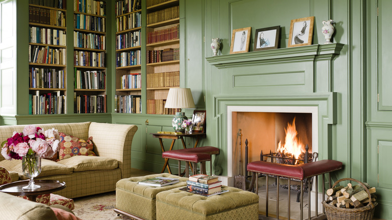 Une bibliothèque vert olive avec une cheminée ornée