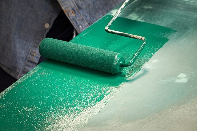 Rouler de la peinture verte sur la surface de la table pour rafraîchir la finition.