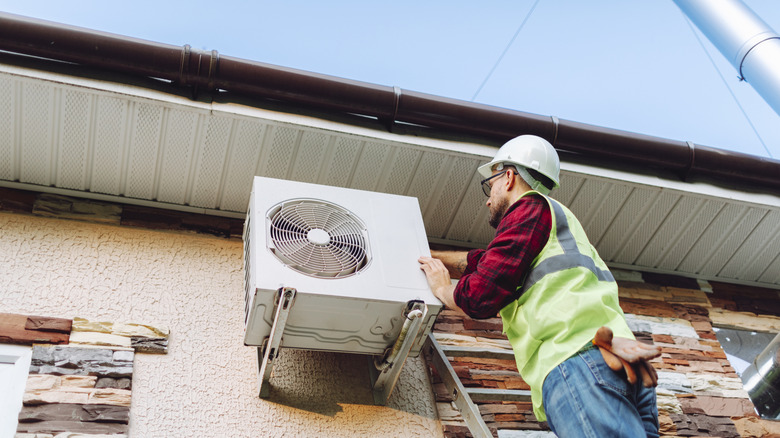 Un technicien travaillant sur une thermopompe à l’extérieur d’un bâtiment