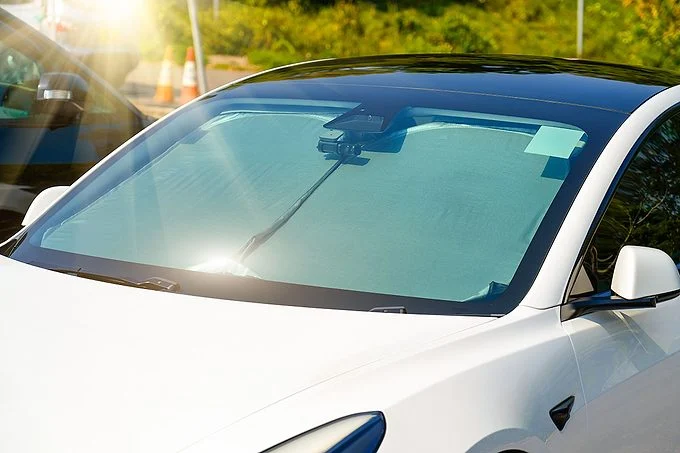 Surface mate réfléchissante protectrice sous le pare-brise de la voiture de tourisme garée par une chaude journée