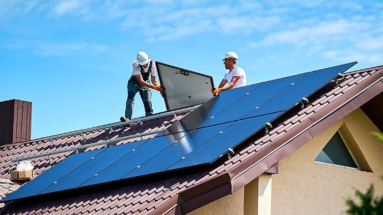 Deux professionnels portant des casques installent des panneaux solaires sur le toit