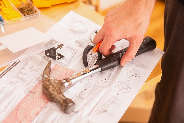 gros plan d'une main atteignant un marteau sur une table