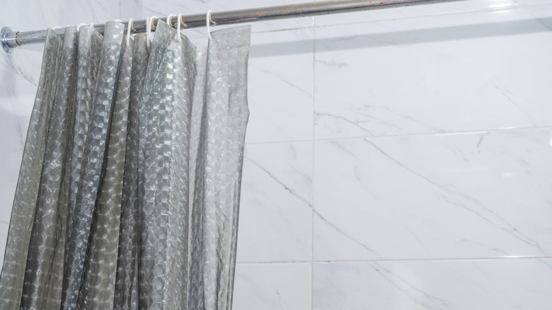 Une salle de bain blanche avec un rideau de douche en plastique.