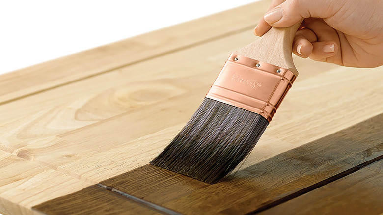 Application manuelle d'une teinture Minwax sur un morceau de bois avec un pinceau Purdy