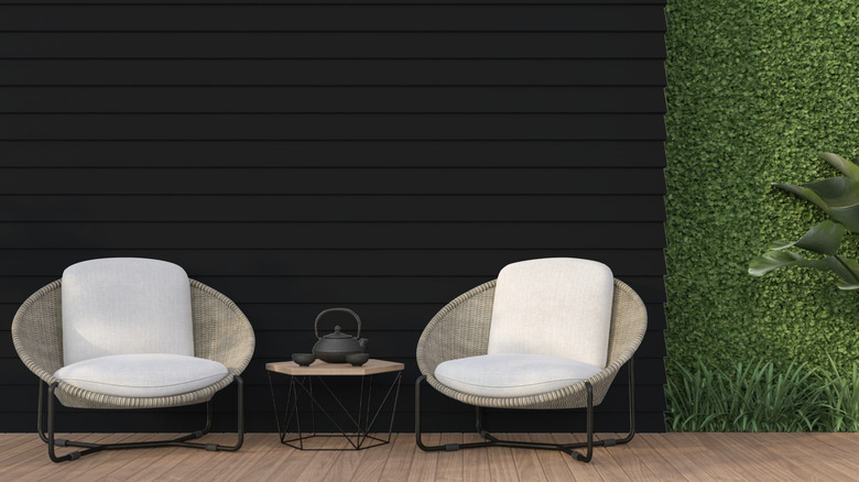 Un mur de terrasse de jardin peint en noir à l'aide d'un produit de peinture Ronseal