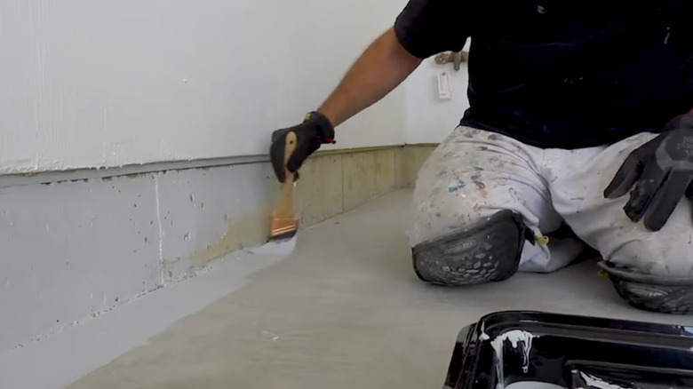 Une personne applique un produit de revêtement pour béton H&C dans un garage