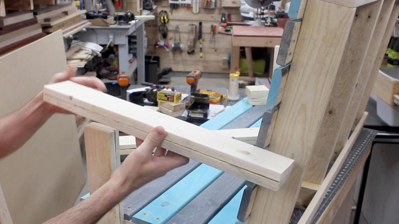 personne tenant du bois pour construire une balançoire de patio en palettes