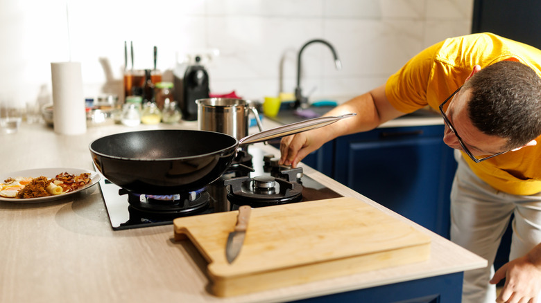 Une personne inspectant et ajustant la flamme d’une cuisinière à gaz.