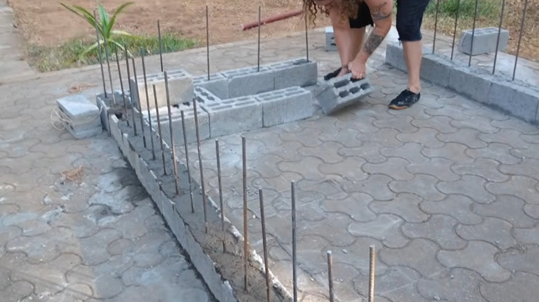 Une personne construisant un mur avec des blocs de béton empilés